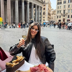 Giacca da moto in pelle nera da donna con occhiali da sole senza montatura e collo alto