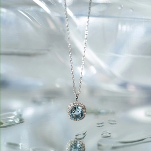 Macro shot of silver aquamarine pendant with sparkling halo diamonds over crystal water