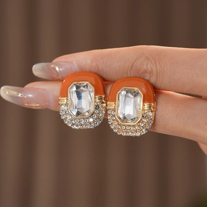 Macro shot of vintage orange enamel earrings with rectangle crystal and rhinestone accents