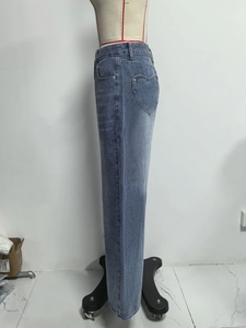 Detail shot of the heart-shaped stitched pocket on light blue high-waisted denim jeans