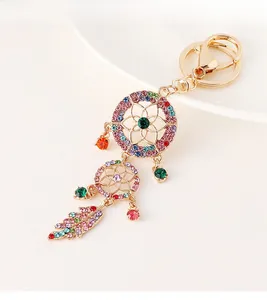 Macro detail of gold dreamcatcher keychain with vibrant colorful rhinestones and feather pendant