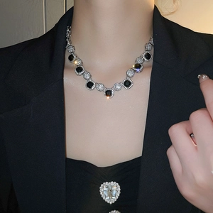Macro view of vintage silver necklace with black gemstone and pavé diamonds on model