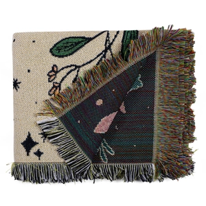 Close-up of woven cotton blanket featuring bohemian whale pattern and colorful tassels