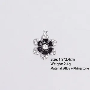 Detail of flower charm with black enamel petals and crystal border on white background