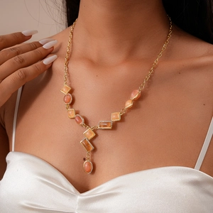 Detail of Y-shaped necklace with gold chain and colorful resin gemstones on a model