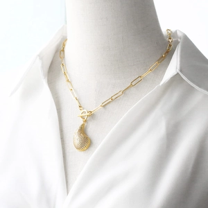 Detail of gold paperclip chain necklace with zircon paved heart pendant and OT toggle clasp