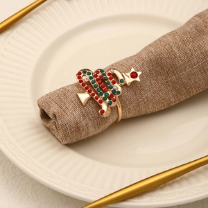 Détail d'un rond de serviette sapin doré serti de strass rouges et verts sur table