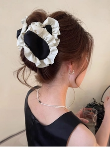 Macro shot of large black and white pleated satin scrunchie styled in a neat hair bun