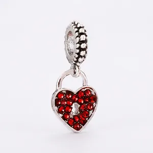 Macro shot of a silver heart lock charm with red crystals and beaded hanging loop