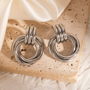 Detail of silver multi-layered interlocking hoop earrings on beige textured stone
