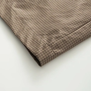 Detailed view of brown checkered fabric texture and high-quality stitching on the garment hem