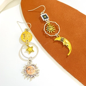 Macro detail of asymmetric vintage earrings with gold and silver celestial motifs