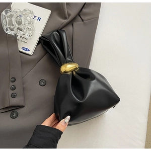 Close-up of black pleated cloud bucket bag featuring a decorative gold metal ring