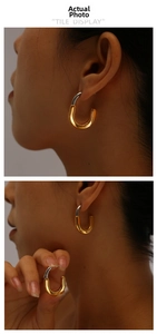 Detail of minimalist 18K gold and silver two-tone U-shaped stainless steel earrings