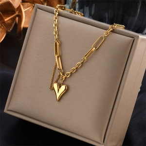 Gold layered necklace with paperclip chain and heart pendant on jewelry box display