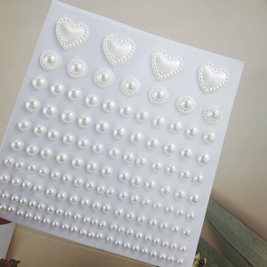 Macro detail of mixed white self-adhesive pearl stickers in heart and flower shapes