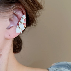 Detail view of gold-plated flower ear cuff with white enamel petals on model ear