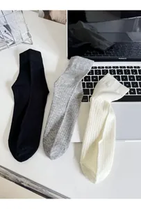 Detailed shot of three pairs of ribbed cotton socks in black, grey and beige colors
