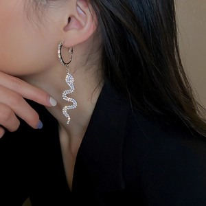 Sparkling silver snake drop earrings with rhinestones worn by a model on black background