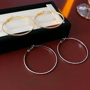 Hammered gold and silver large hoop earrings displayed on a luxury black jewelry box