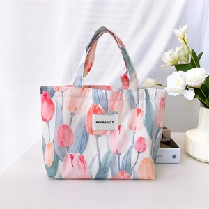 Detail view of floral tulip canvas handbag with May Rabbit woven label on white fabric