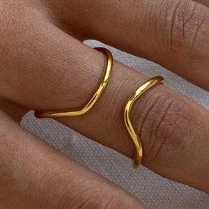 Close-up of minimalist 18k gold-plated wavy and V-shape rings stacked on fingers