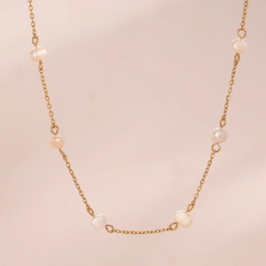 Detail of minimalist gold chain necklace with six round white freshwater pearls
