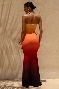 Macro detail of sunset gradient fabric and palm leaf shadows on strapless maxi dress