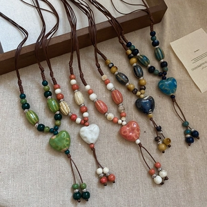 Détails de colliers en céramique avec pendentif cœur sur un fond de lin rustique