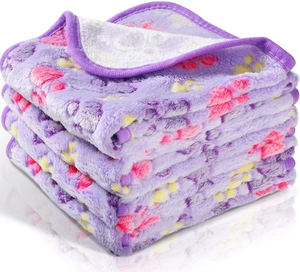 Close-up of stacked purple flannel pet blankets with colorful paw print patterns