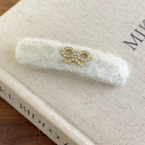 Detailed view of plush beige hair clip with sparkling rhinestone golden bow on a book