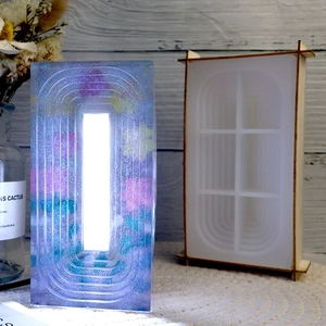 Detail of rectangular silicone mold next to finished floral resin lamp with purple LED glow