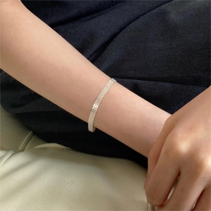 Detailed view of silver mesh woven bracelet worn on wrist for an elegant fashion style