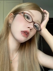 Close-up of retro oval brown eyeglasses frame worn with silver jewelry accessories