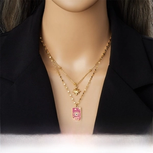 Double-layered gold necklace with pink enamel eye pendant and star charm on a model