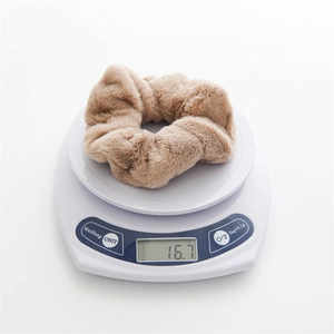 Detail shot of a soft brown rabbit fur scrunchie on a digital scale weighing 16.7g