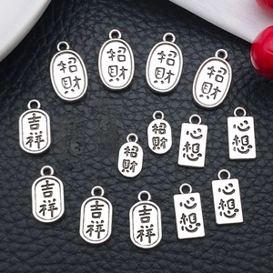 Detailed view of silver alloy amulets with Chinese characters on black leather background