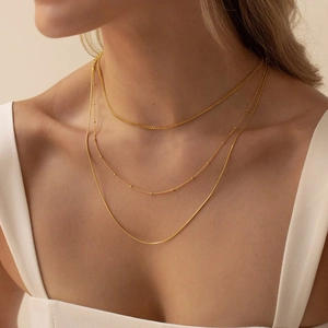 Detailed view of layered gold-plated necklaces featuring rope, satellite and snake chains