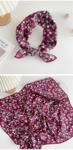 Detail of burgundy floral square scarf showing hemmed edges and silk texture on white surface