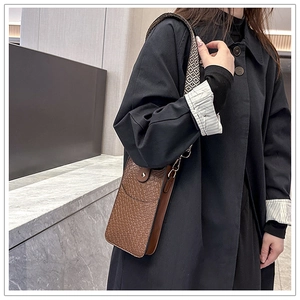 Detail der braunen Handyhülle aus geprägtem Leder mit stylischem gewebtem Schultergurt