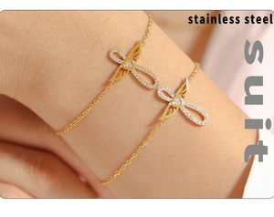 Détail de bracelets aile d'ange et cœur dorés avec zircons portés au poignet