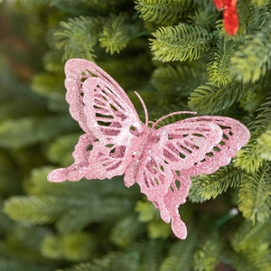 Pink glitter butterfly ornament with cutout design hanging on a Christmas tree branch