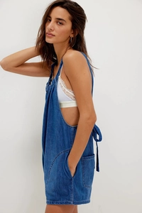 Detail of adjustable back straps and cargo pockets on dark blue denim jumpsuit
