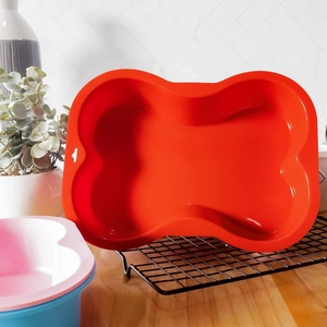 Red bone-shaped silicone baking mold for creative pet treats on a metal cooling rack