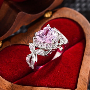 Detailed macro of a heart-shaped pink gemstone ring with bow-shaped silver band