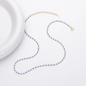 Detail of gold chain necklace featuring small blue beads and a spring ring clasp