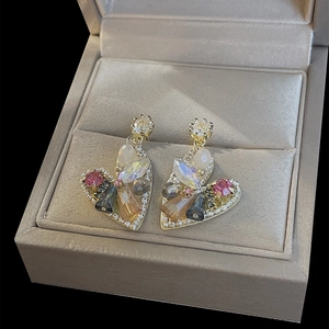 Macro detail of heart earrings with colorful crystals and pearls in a jewelry box