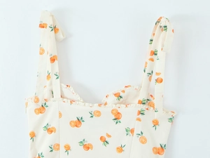 Detail of adjustable bow shoulder straps and orange print lace trim on summer dress