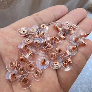 Primo piano di chiusure per orecchini in plastica trasparente e bronzo tenute in un palmo