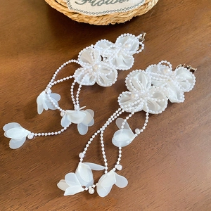 Close-up of elegant white chiffon petal earrings with faux pearl center and fringe tassels